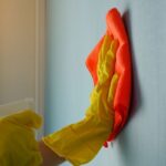 persona che pulisce parete di casa